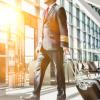 Commercial airline pilot walking in airport terminal with roller bag
