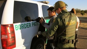 A Border Patrol agent by an SUV stopping a heavy-duty truck